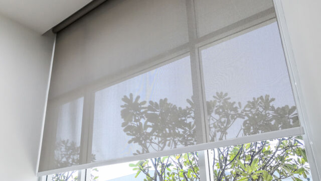 Roll Blinds on the windows, the sun does not penetrate the house. Window in the Interior Roller Blinds. Beautiful Blinds on the Window, the Sun and Heat Protection, the Perfect Windows Interior Decor screens