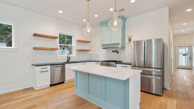 Designer kitchen with wood open shelving, state-of-the-art appliances, and vintage-inspired lighting.