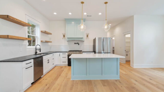 Designer kitchen with wood open shelving, state-of-the-art appliances, and vintage-inspired lighting.