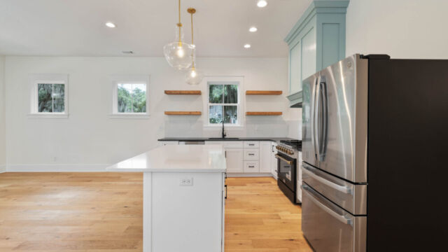 Designer kitchen with wood open shelving, state-of-the-art appliances, and vintage-inspired lighting.