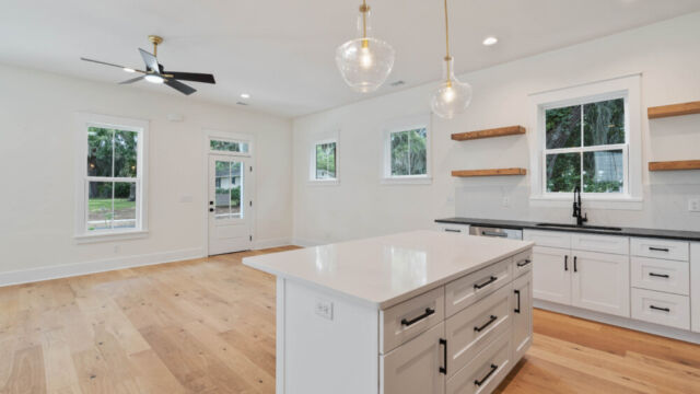 Designer kitchen with wood open shelving, state-of-the-art appliances, and vintage-inspired lighting.