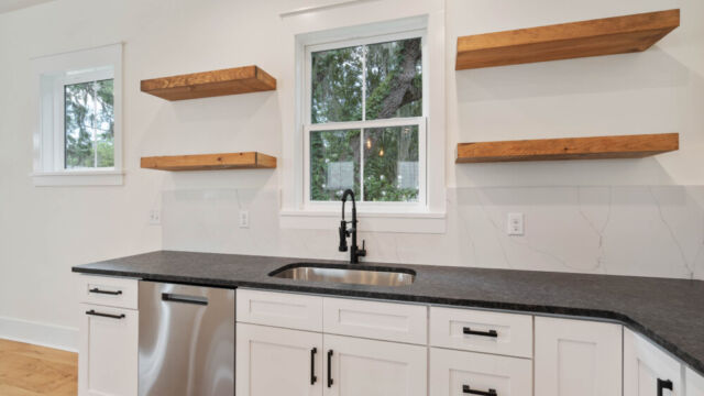 Designer kitchen with wood open shelving, state-of-the-art appliances, and vintage-inspired lighting.