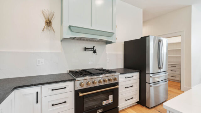 Designer kitchen with wood open shelving, state-of-the-art appliances, and vintage-inspired lighting.