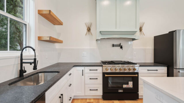 Designer kitchen with wood open shelving, state-of-the-art appliances, and vintage-inspired lighting.