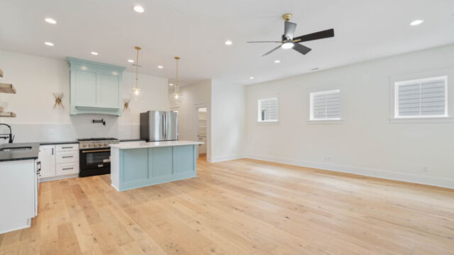 Designer kitchen with wood open shelving, state-of-the-art appliances, and vintage-inspired lighting.