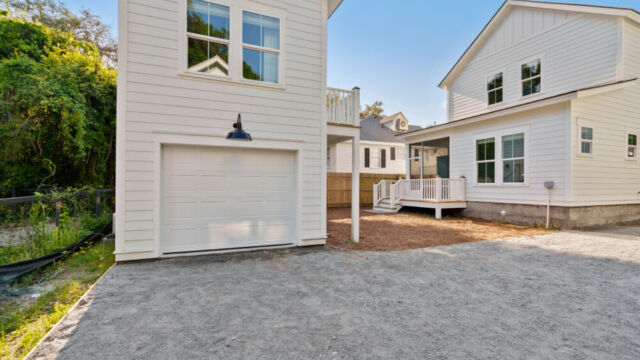 Detached garage with a modern studio apartment above, featuring exterior stairs and large windows.