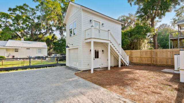 Detached garage with a modern studio apartment above, featuring exterior stairs and large windows.