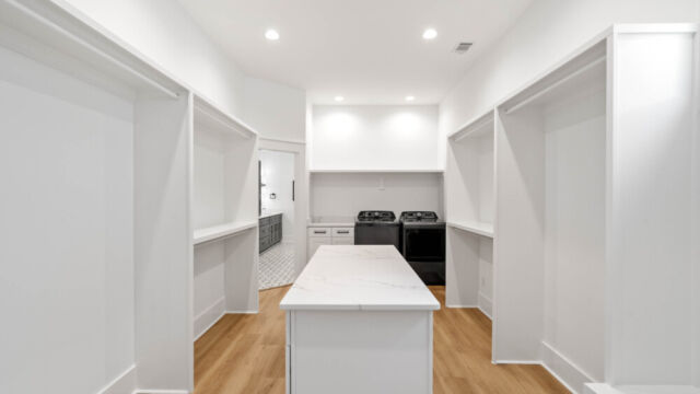 Spacious primary closet featuring built-in storage and laundry area.