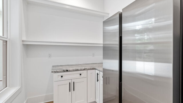 Large pantry featuring a full-size fridge and shelving for organization.